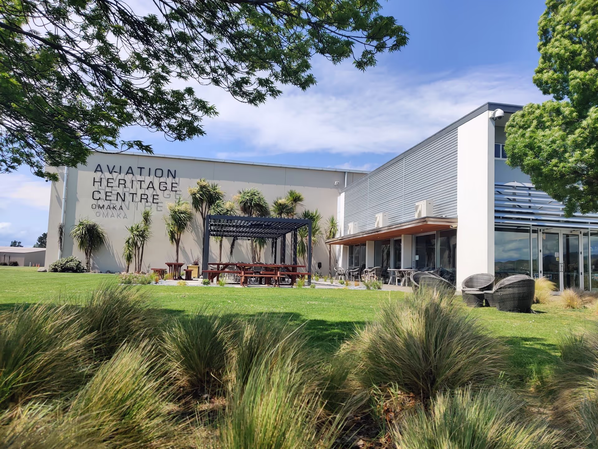 Exterior view of Aviation Heritage Centre with grassy lawn and outdoor seating area.