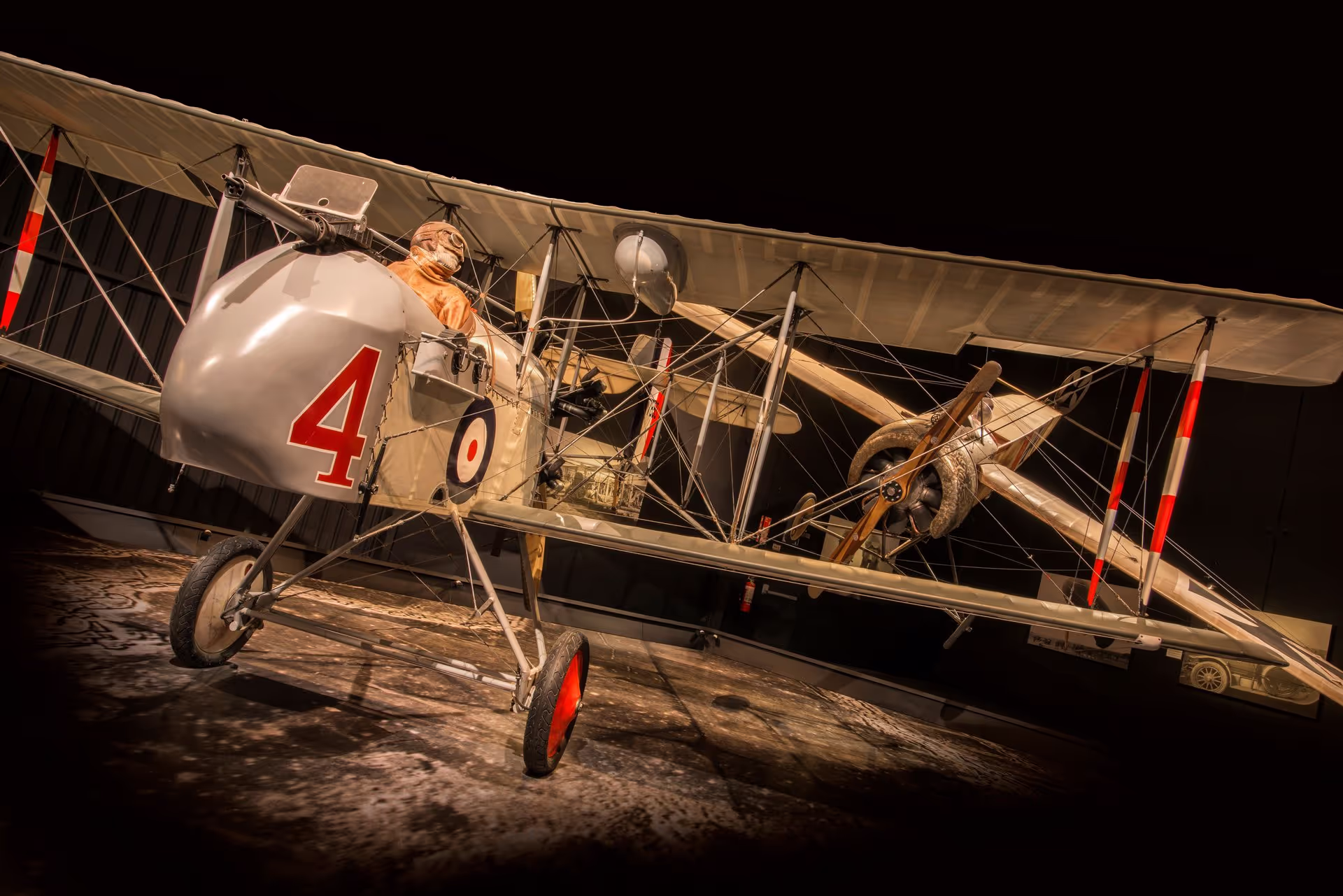 Vintage biplane with pilot figure on display, marked number "4" on a dark background.