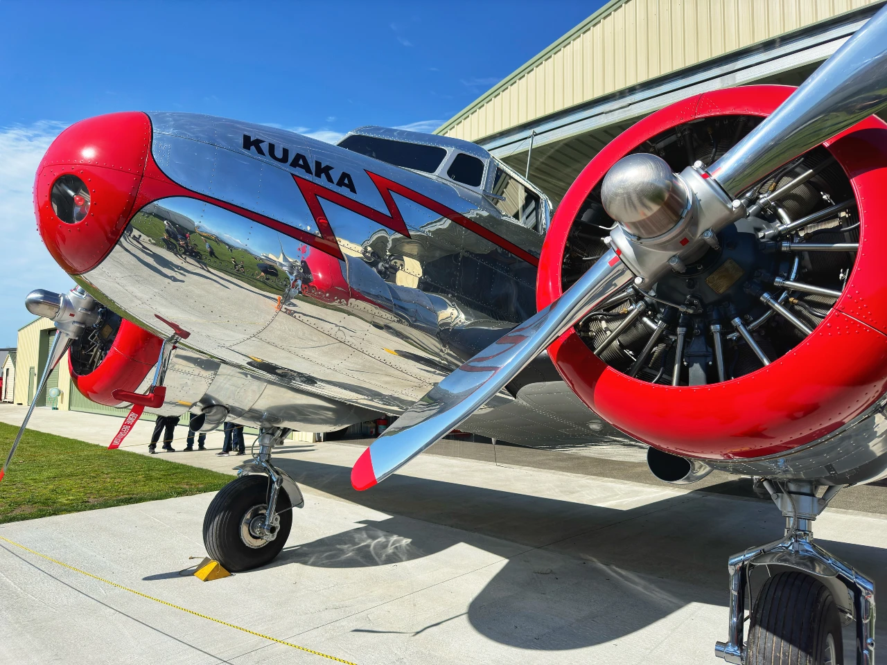 Pristine silver Lockheed 10A aircraft with red trim on display outside its hangar at Omaka.