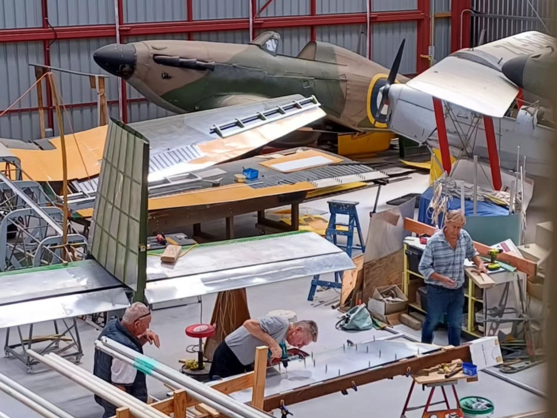 Shows the Omaka Hangar workshop floor and a skilled volunteer working on a plane.