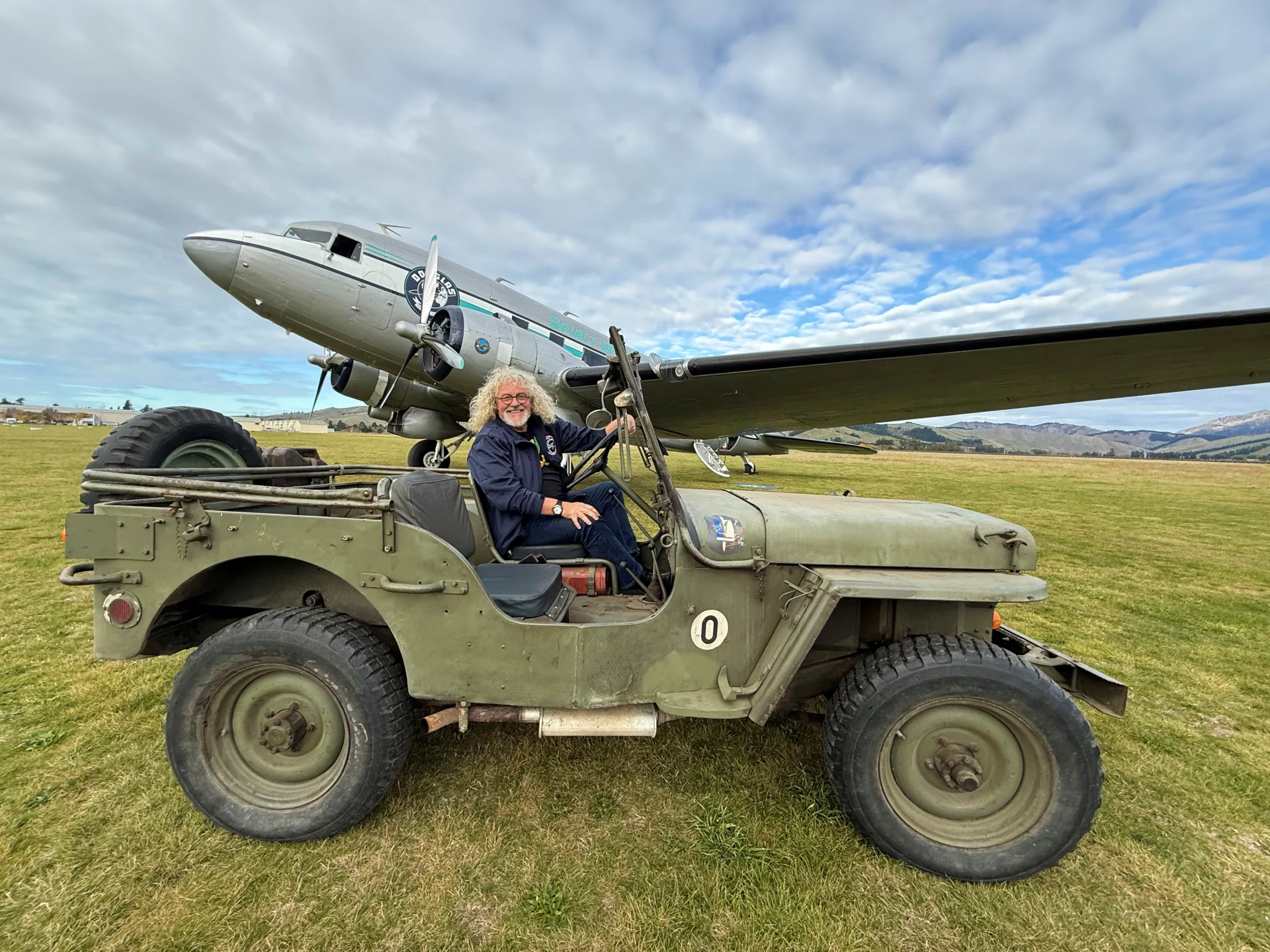 Spirit of Douglas DC-3 parked at Omaka, with Mark Stewart seated in a vintage military jeep in the foreground.