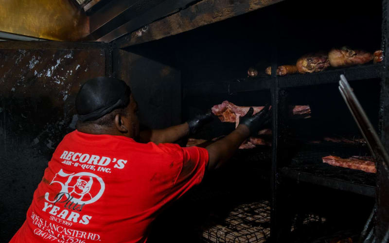 Pitmaster tending ribs at a commercial smoker during a brand photography session