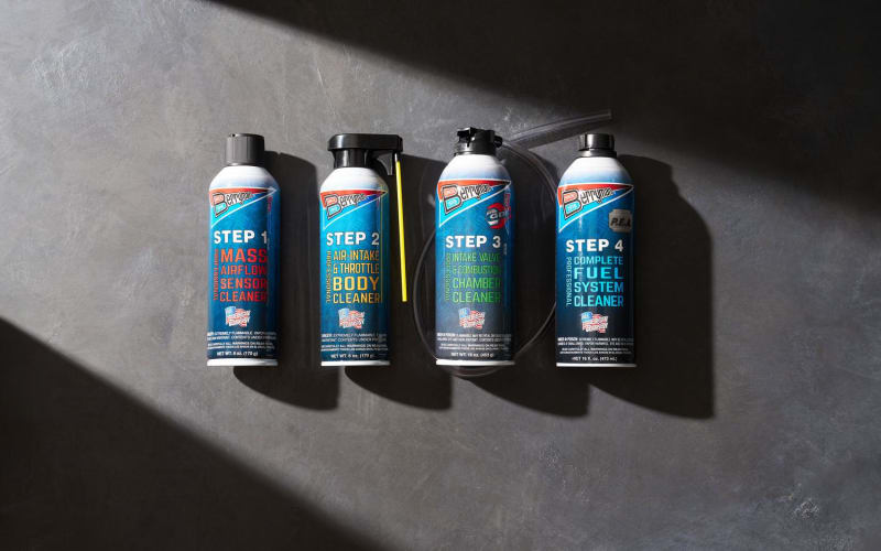 Four automotive cleaning products arranged sequentially under dramatic directional lighting