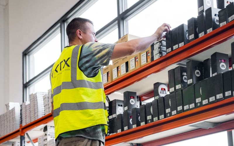 Warehouse worker in safety vest organizing inventory on industrial shelving