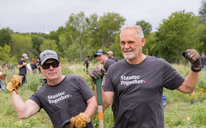 Two team members in branded shirts posing with tools during a corporate volunteer event