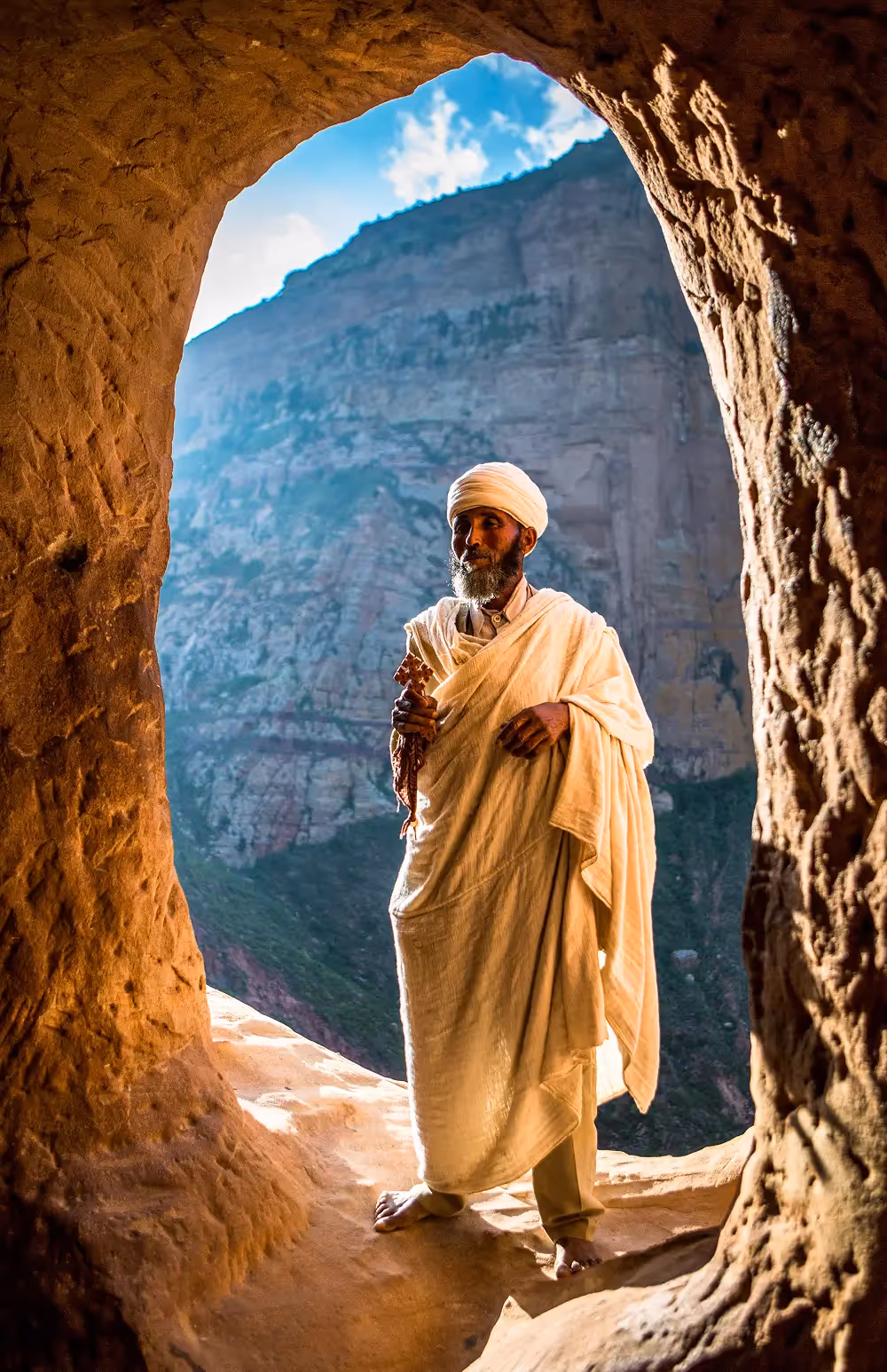 Ethiopian man standing at cave entrance