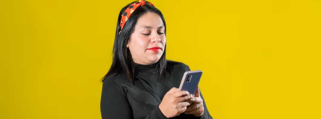 Una mujer luciendo feliz mientras usa su teléfono payjoy.