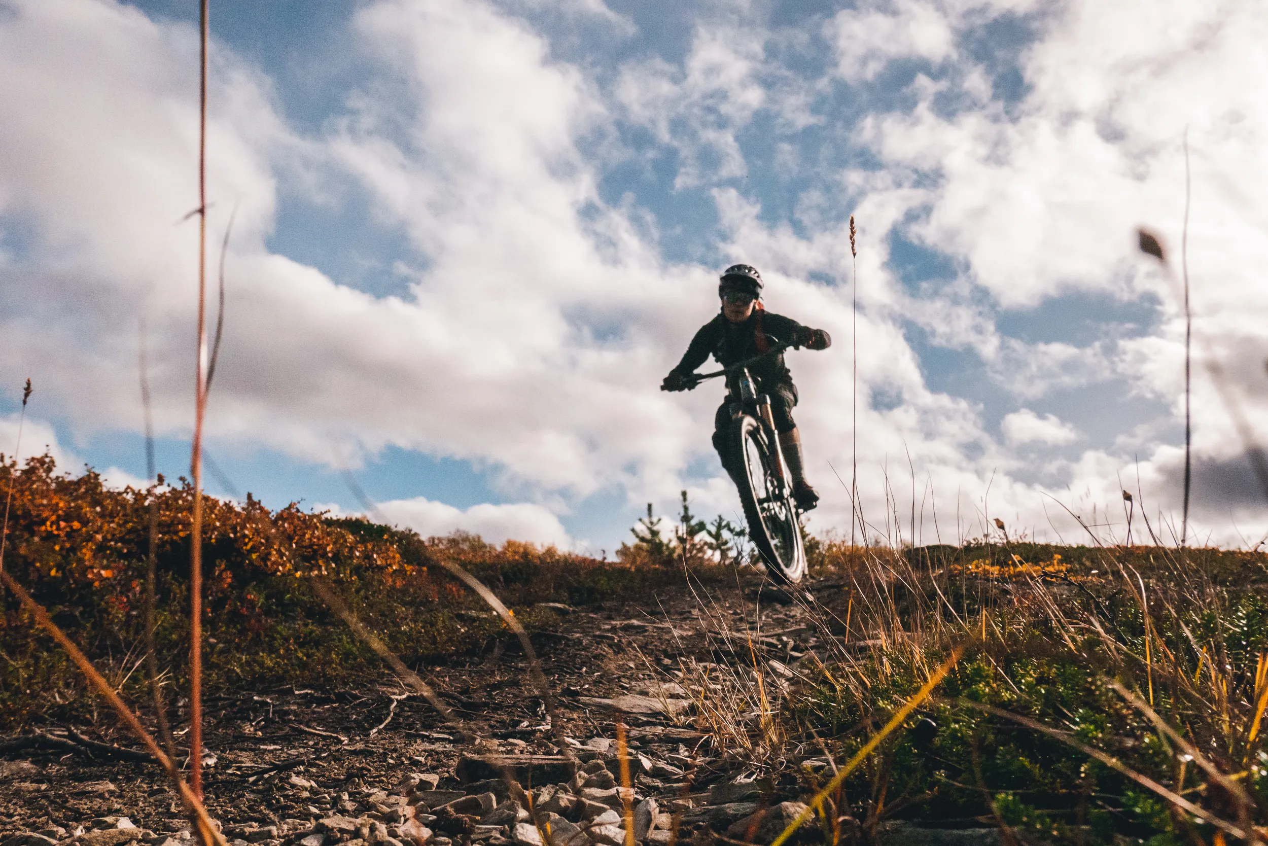 gutt kjører mountainbike i åpent landskap