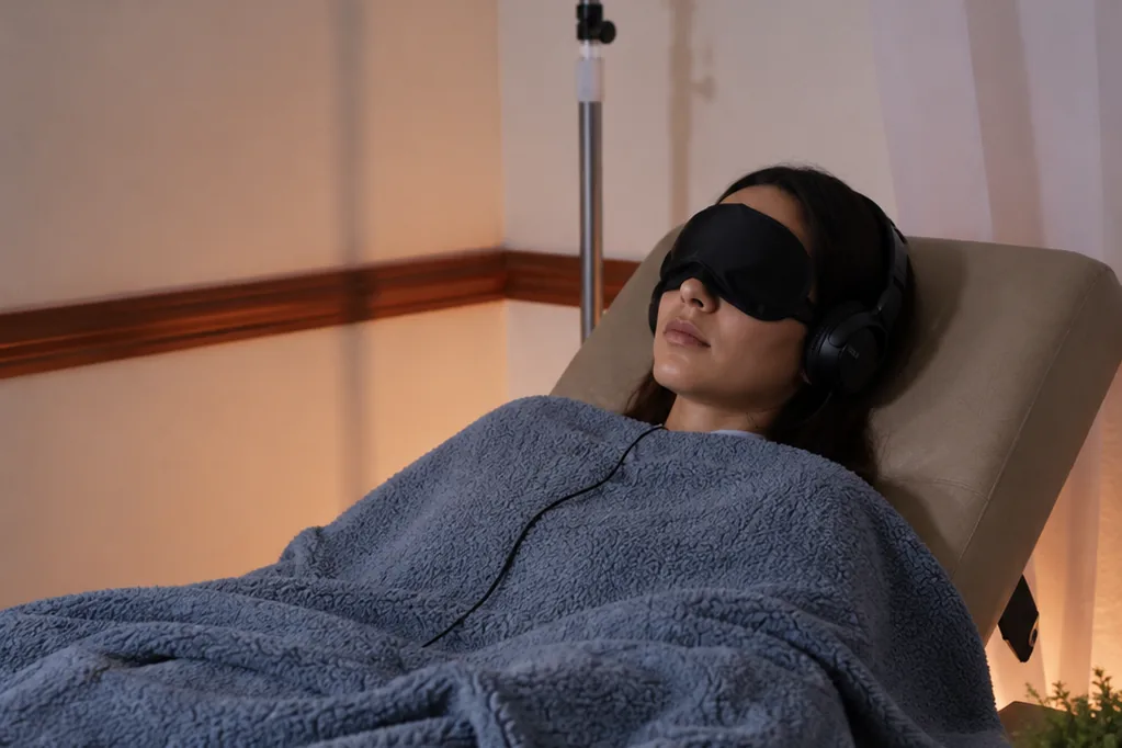 Patient resting under a blanket with an eye mask and headphones during a monitored Spravato session at ARC Mental Health