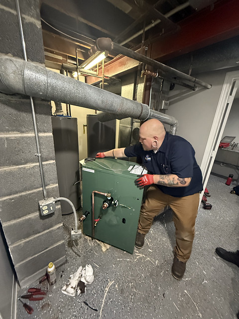 HVAC technician installing or adjusting a heat pump unit in basement