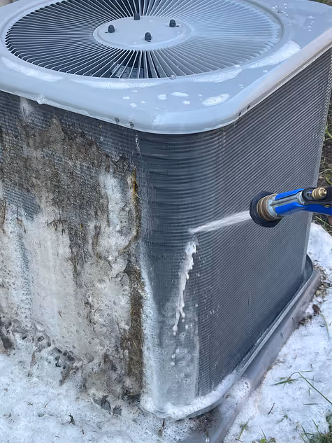 Outdoor AC condenser being cleaned with water and coil cleaner spray.