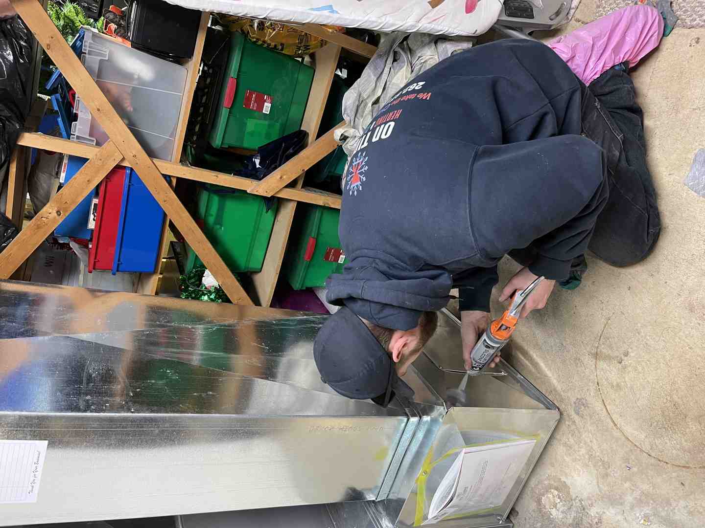 HVAC technician sealing duct connections during AC installation in a basement HVAC technician sealing duct connections during AC installation in a basement