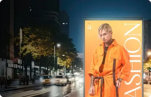 Night street scene with illuminated fashion advertisement featuring a blond man in an orange outfit.