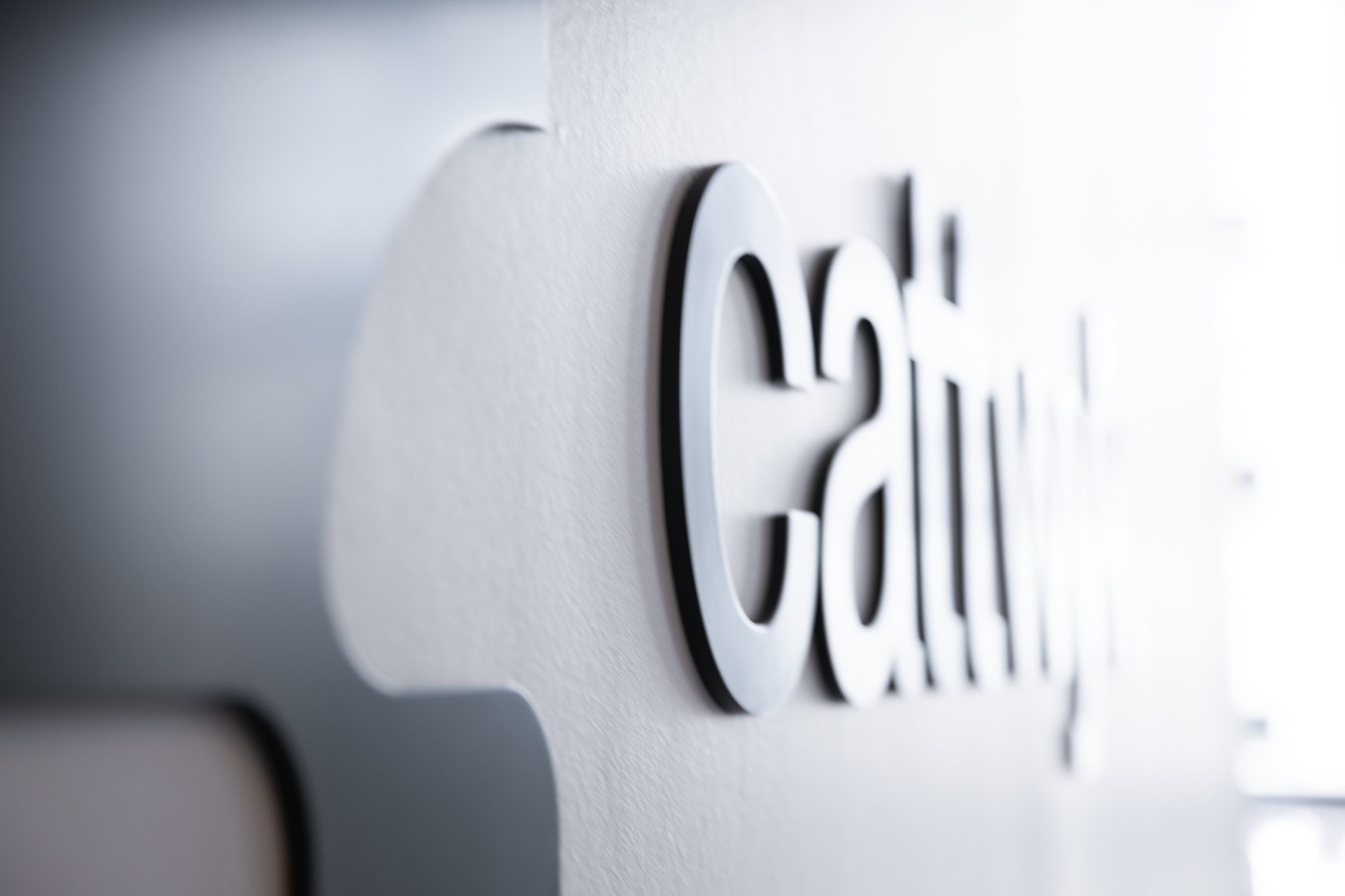 Three pairs of hands on a dark table with a bowl of oranges, two glasses, and an open magazine.