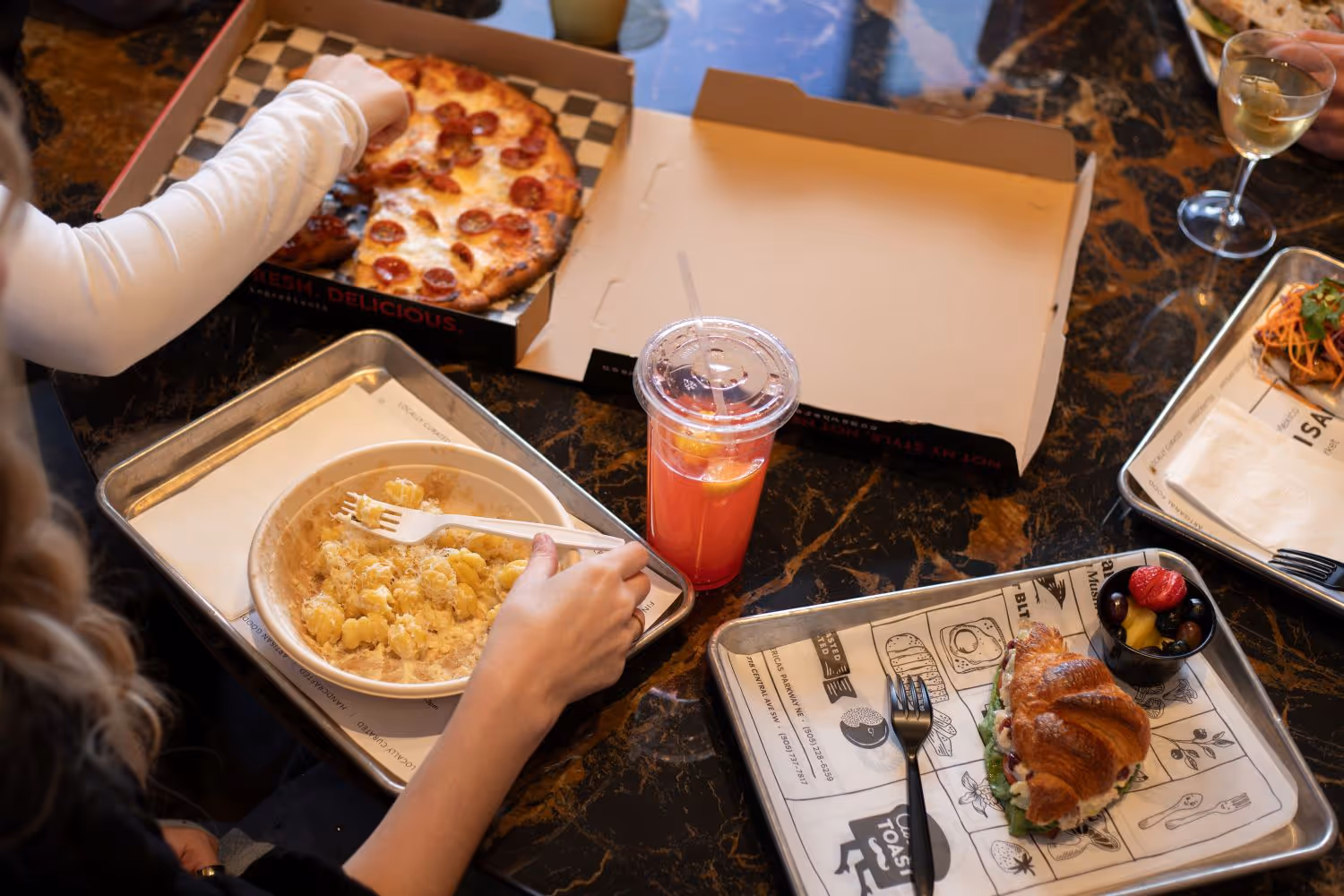 A variety of dishes on trays to include pasta, pizza, sandwiches