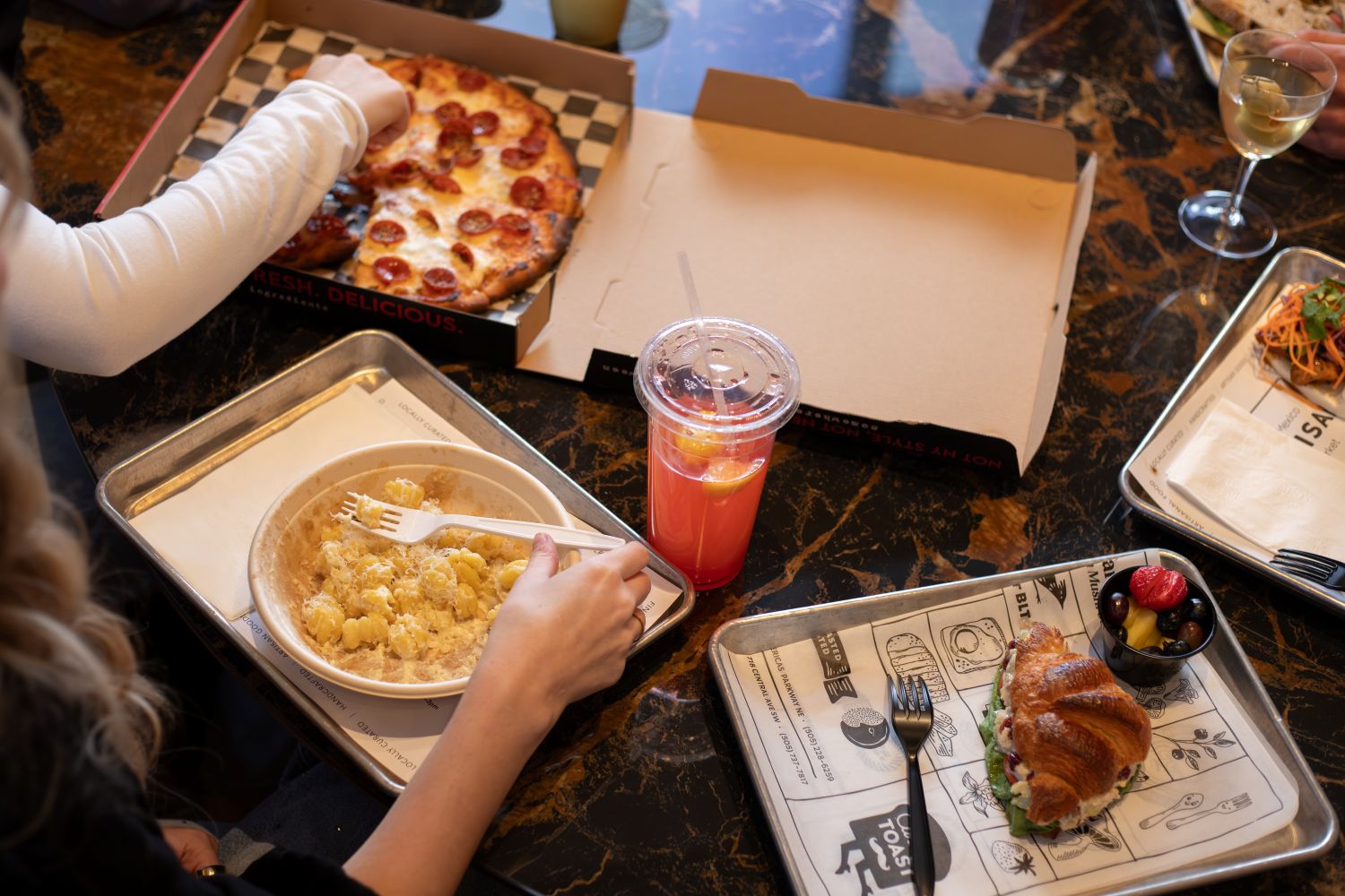 A variety of dishes on trays to include pasta, pizza, sandwiches