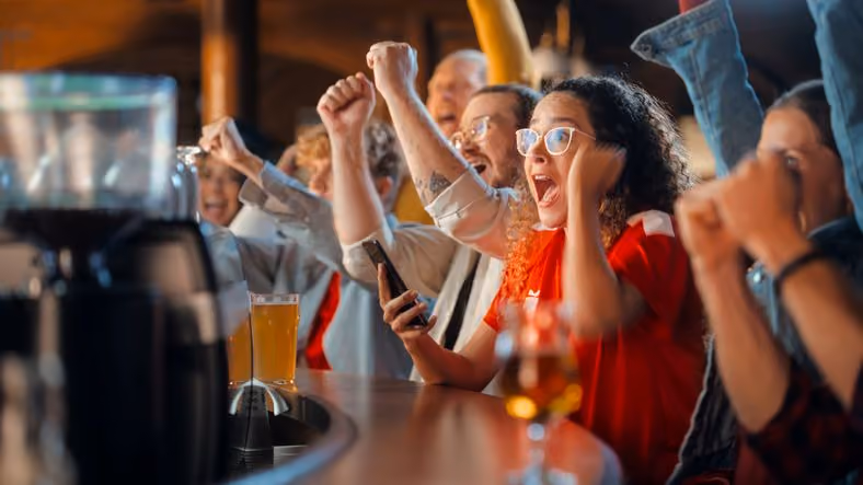 Group of people sitting at bar cheering in unison