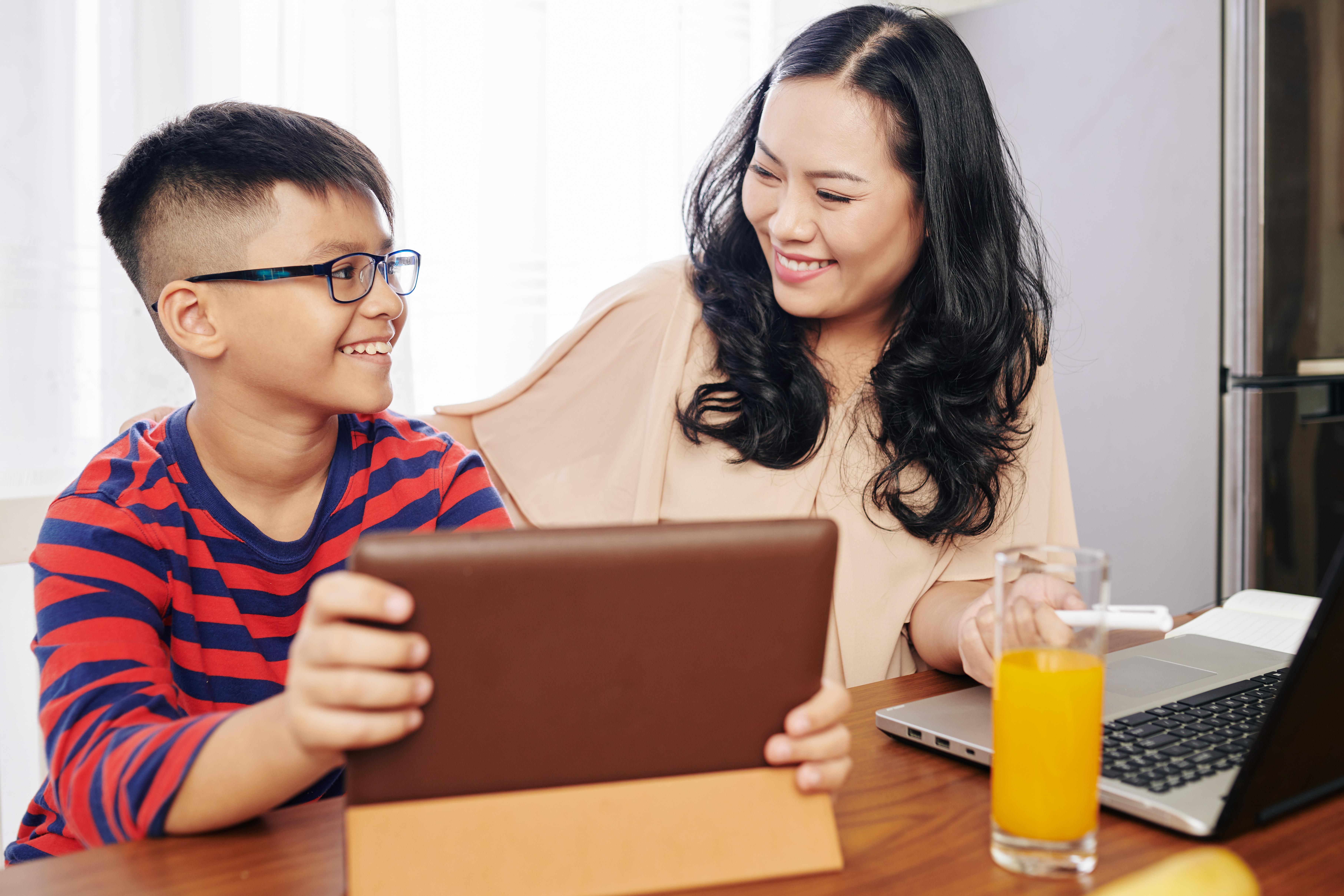 Smiling child showing a tablet to a parent after playing an educational game