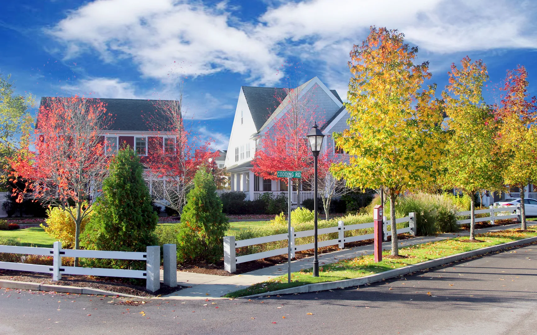 Autumn streetscape with vibrant foliage at Red Mill Village, 55+ community in Norton MA