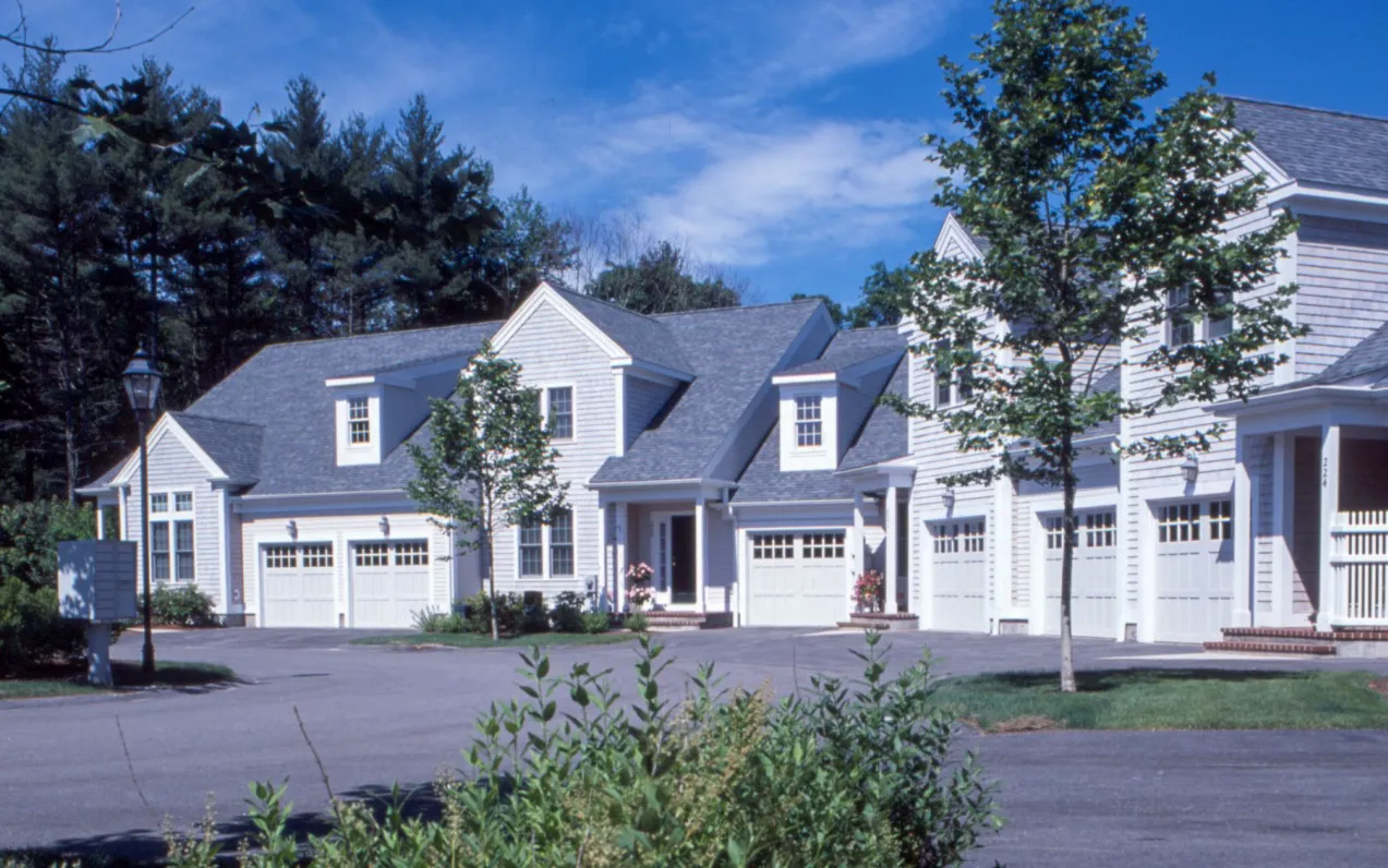 Multi-unit attached homes with garages surrounded by mature trees at GreatBrook Norton MA