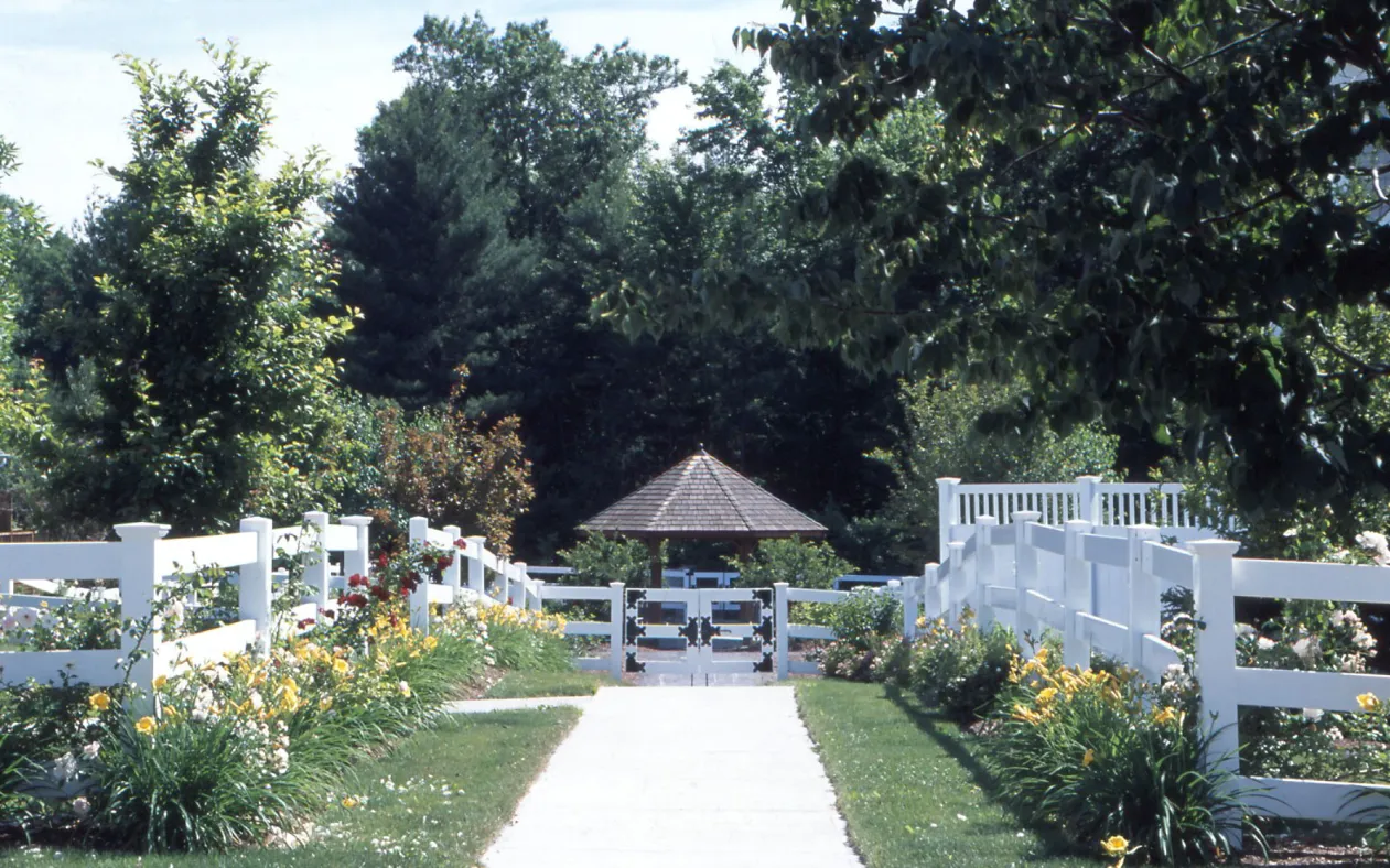 Garden gazebo pathway with white fencing and summer blooms at GreatBrook in Norton MA