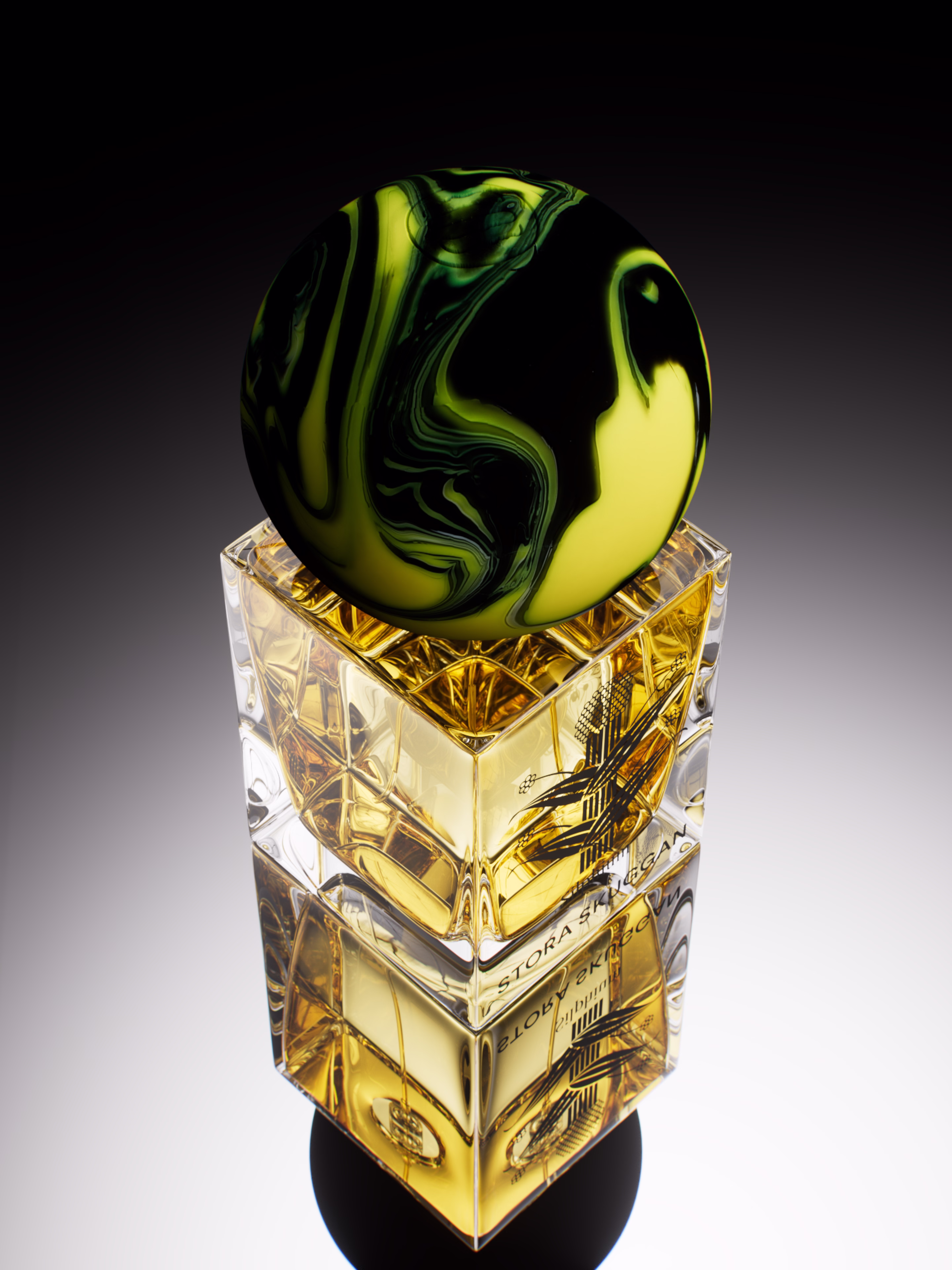 Square glass perfume bottle with amber liquid and a marbled globe-shaped cap on top.