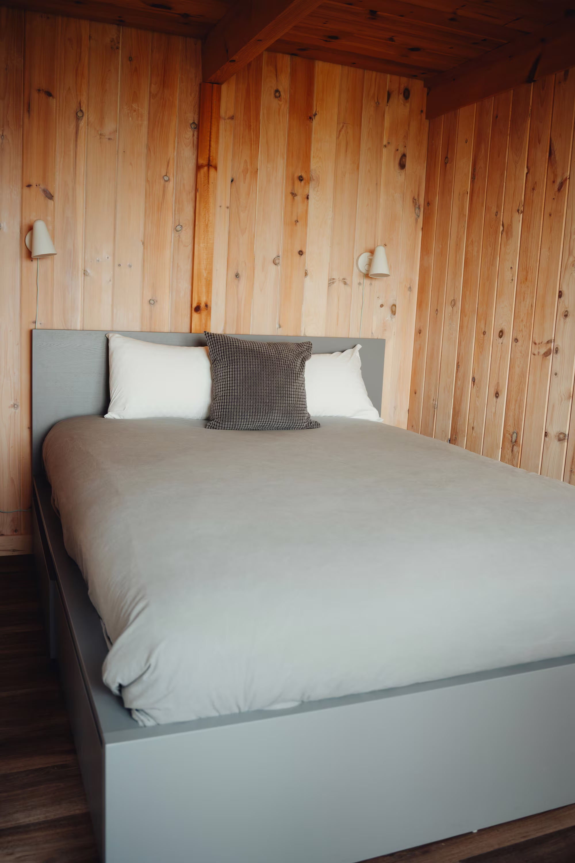 Chambre du chalet arrière avec lit queen et murs lambrissés de bois