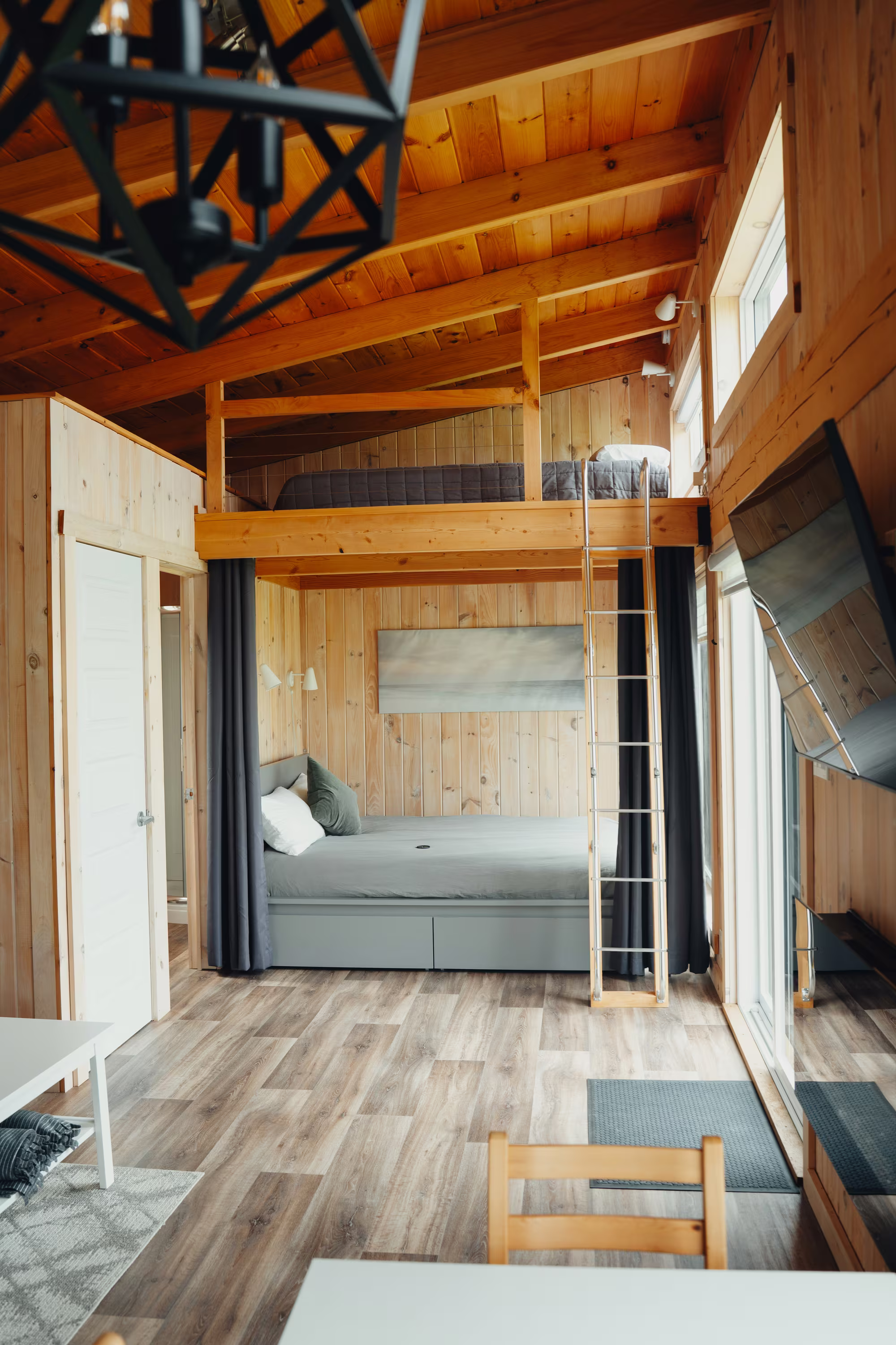 Mezzanine et séjour du chalet arrière sous le plafond de bois