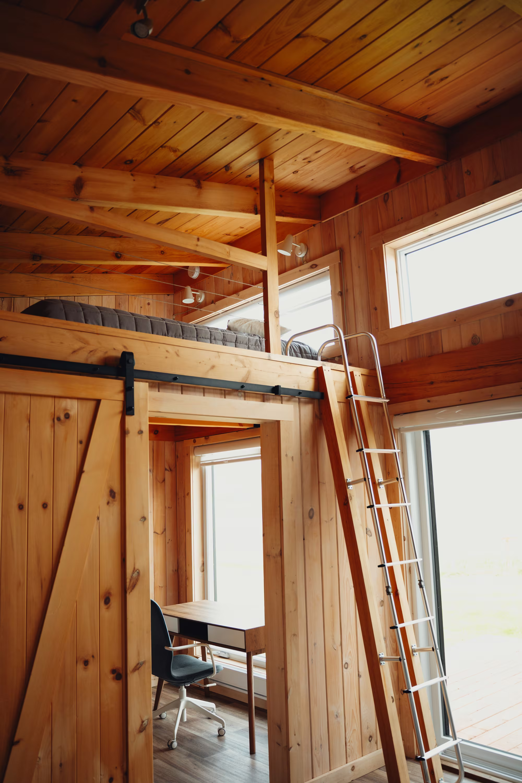 Mezzanine du chalet double accessible par échelle, avec porte-grange