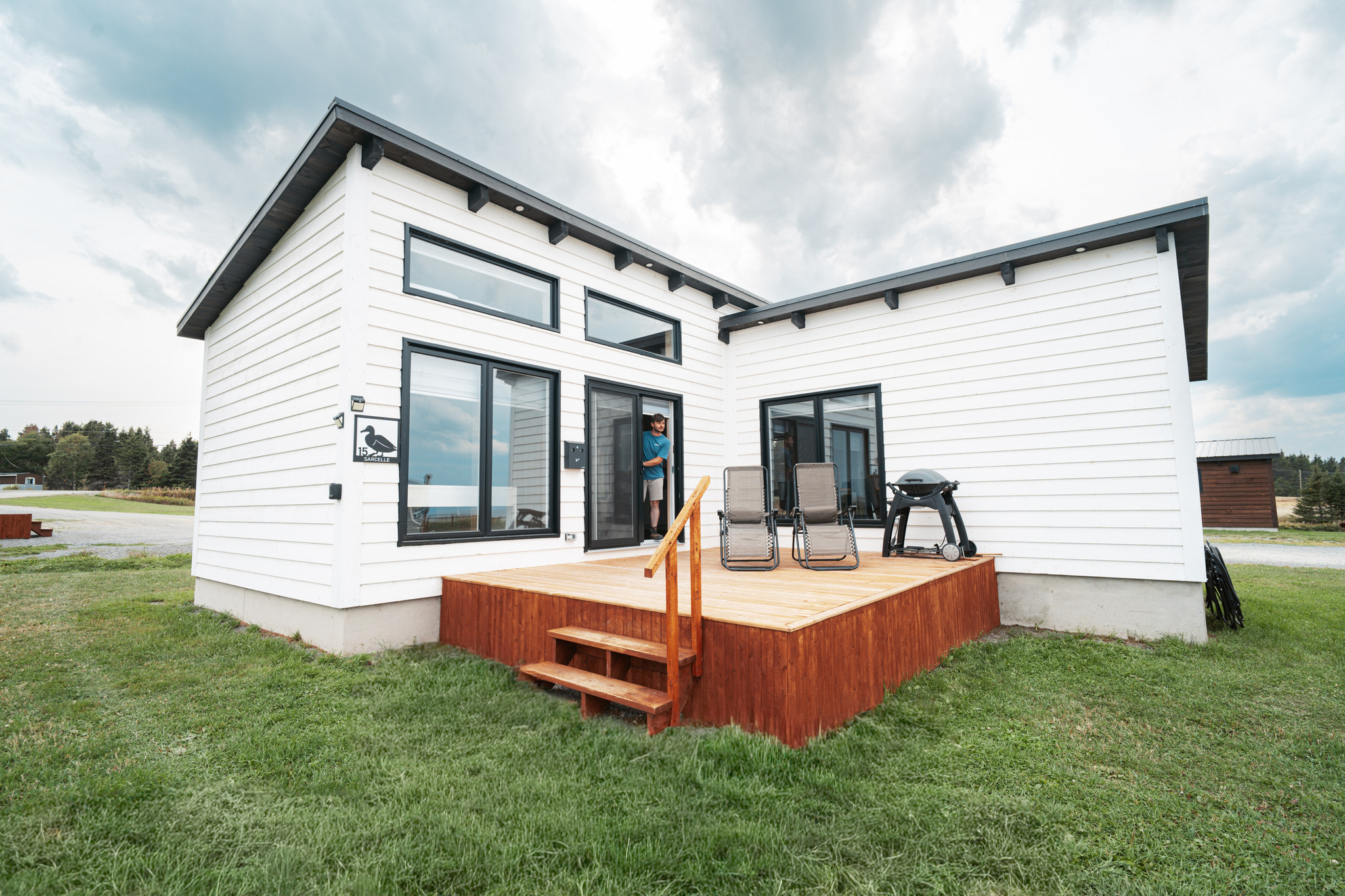 Extérieur d'un chalet double blanc avec terrasse et BBQ
