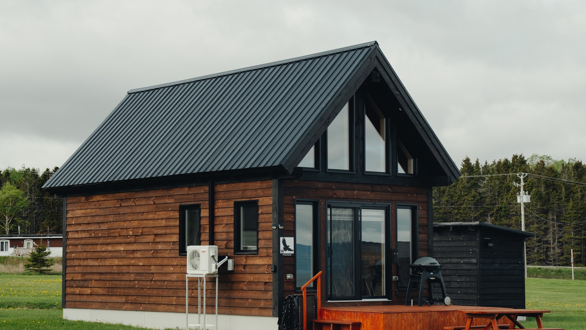 Le chalet style suisse vu de face, toit en pignon et terrasse de bois