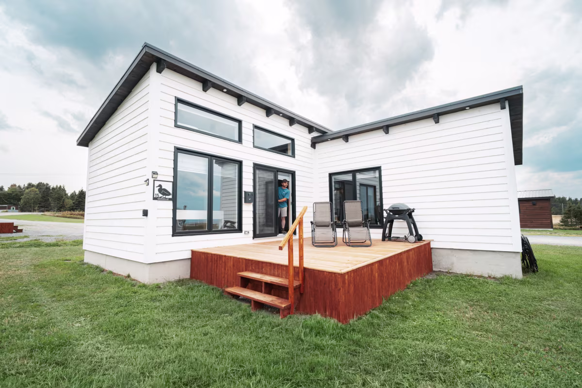 Außenansicht eines weißen Doppelchalets mit Terrasse und Grill