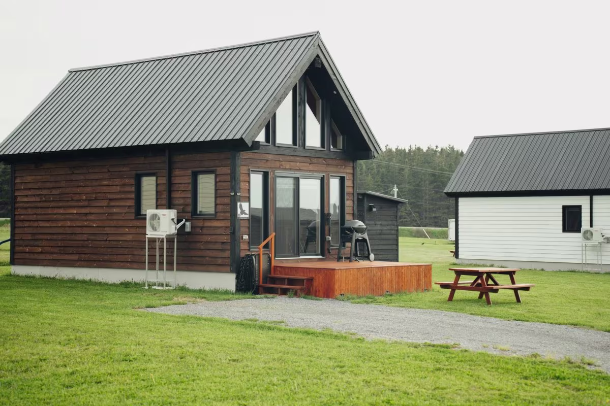 La façade vitrée en pignon, sur la pelouse du chalet style suisse