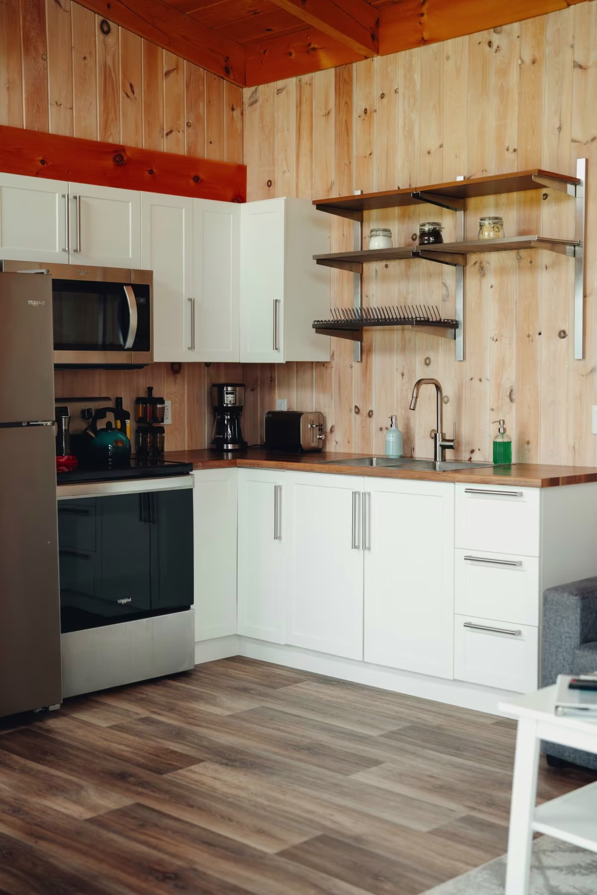 Die Einbauküche mit weißen Schränken, Mikrowelle und offenen Regalen im vorderen Teil des Chalets