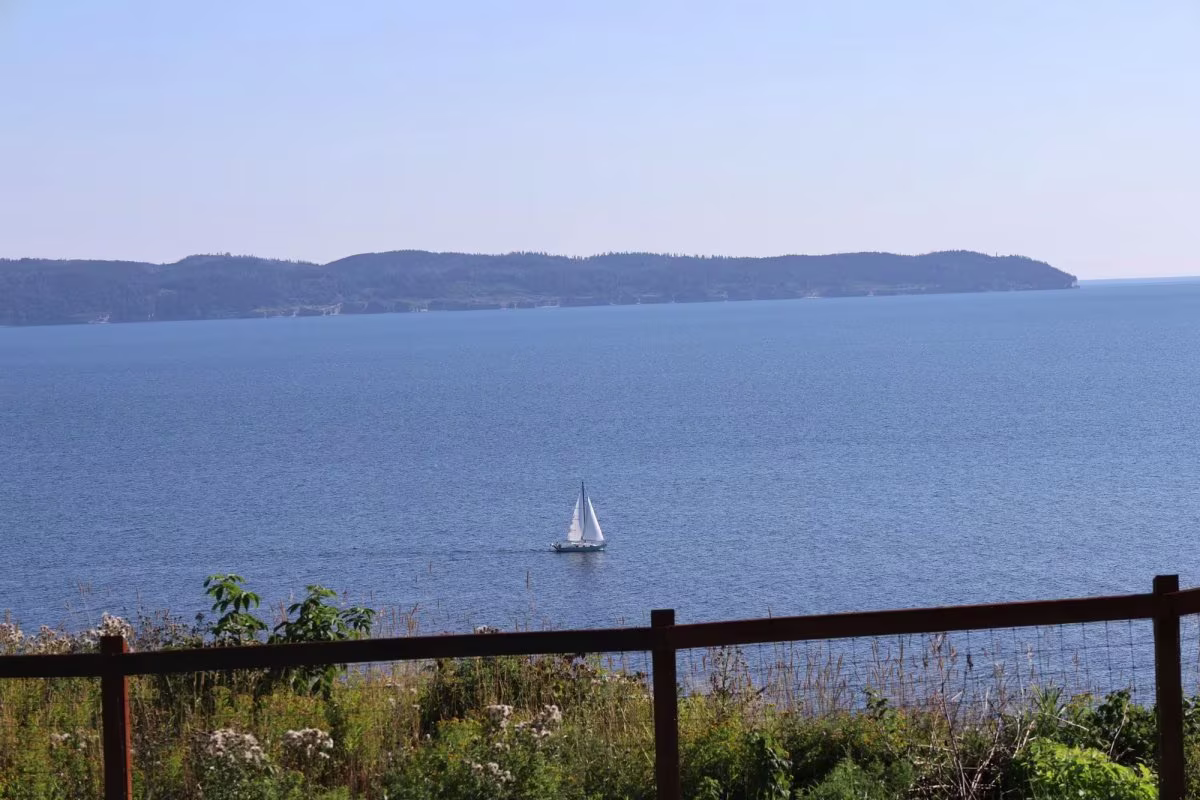 Der Blick auf die Bucht von Gaspé vom Grundstück aus, mit einem Segelboot vor der vorderen Doppelhütte