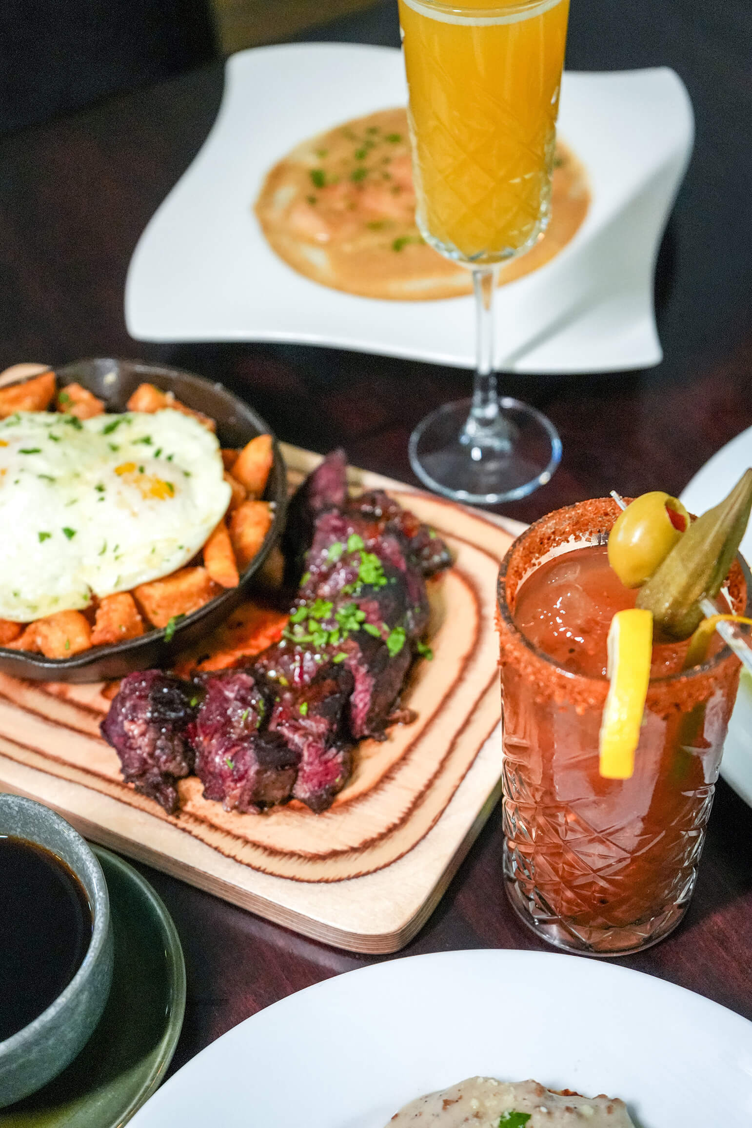 steak, potatoes, eggs and mixed drinks on table