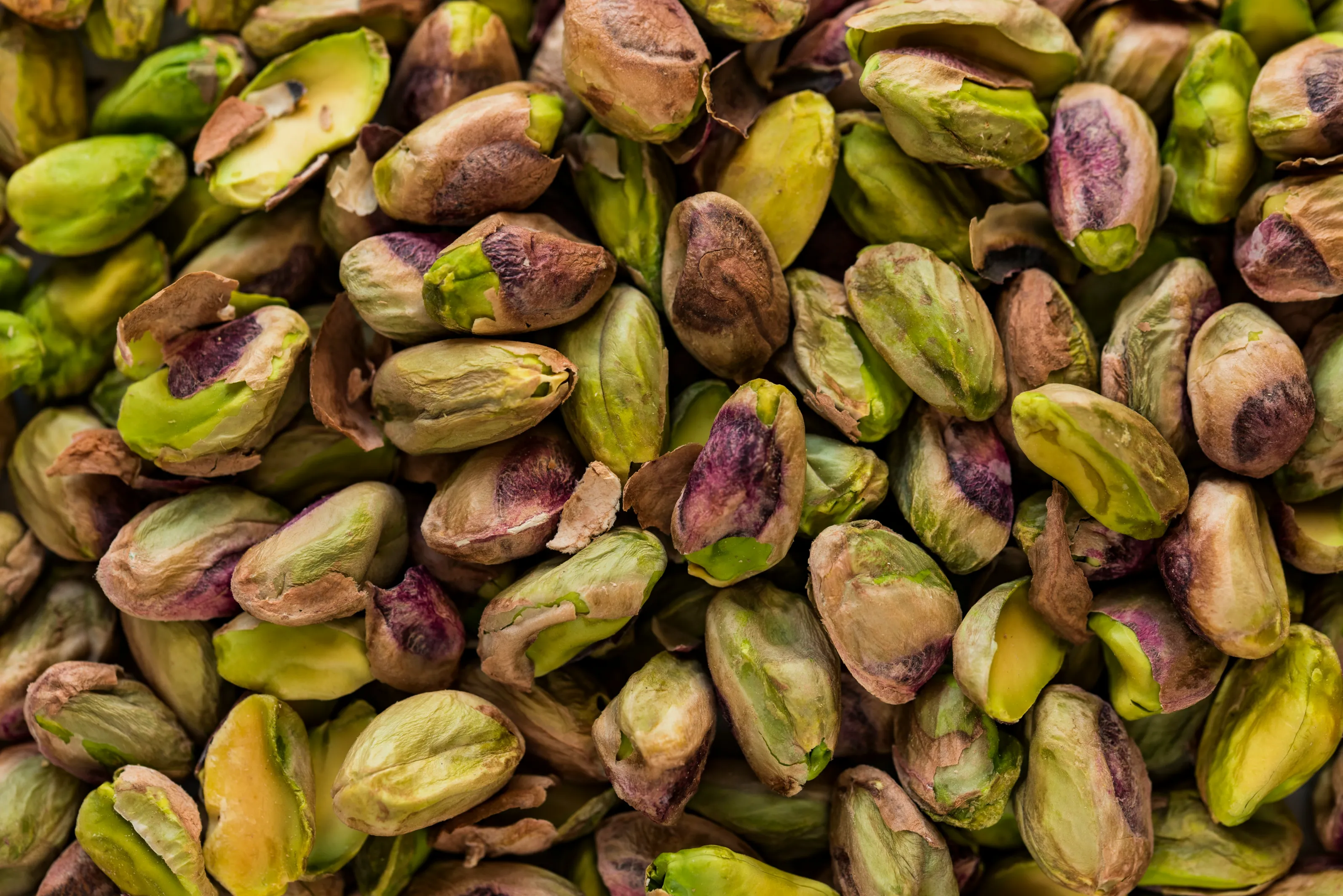 Tight macro of shelled pistachios showing vivid green kernels with purple blush. The frame is filled edge-to-edge, highlighting freshness, quality, and hand-selected grading consistent with Sharon Naraghi Farms’ sustainably cultivated San Joaquin Valley harvests.