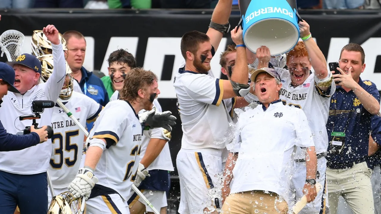 Notre Dame men's lacrosse players celebrating a championship win by pouring a cooler of water over head coach Kevin Corrigan.