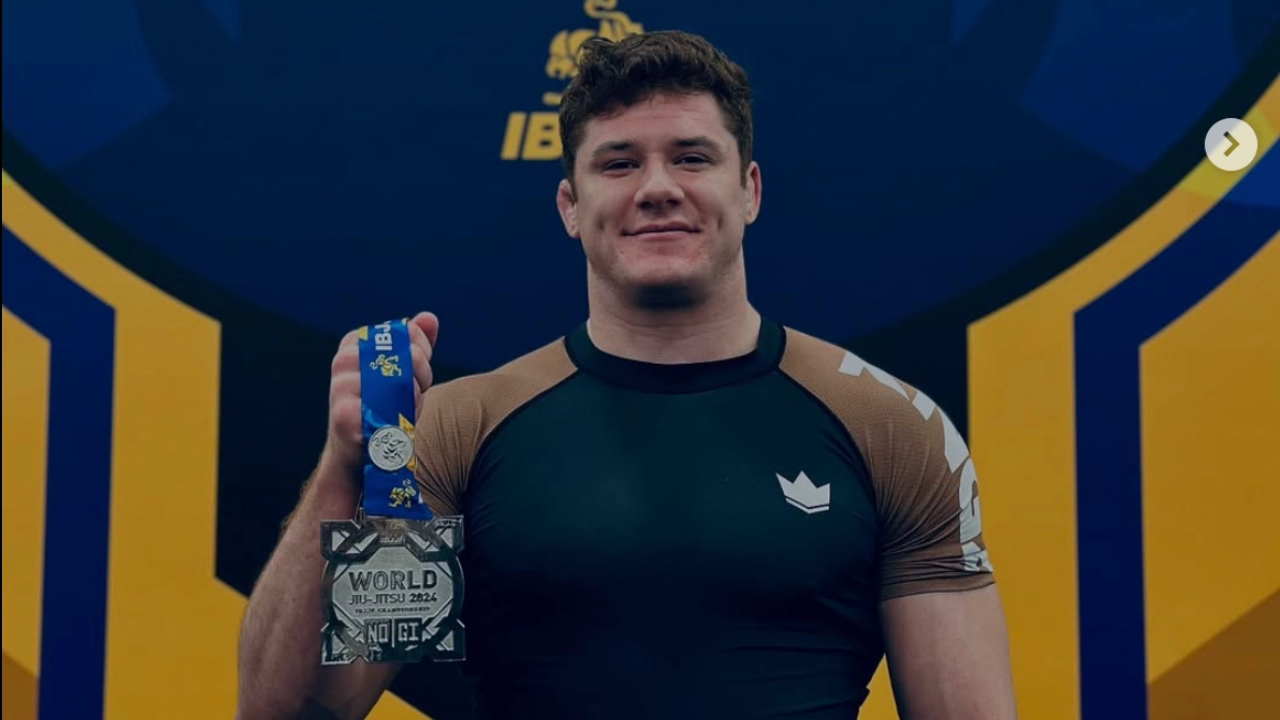 Marymount University men's lacrosse coach instructing players in blue chrome helmets during a focused team huddle.