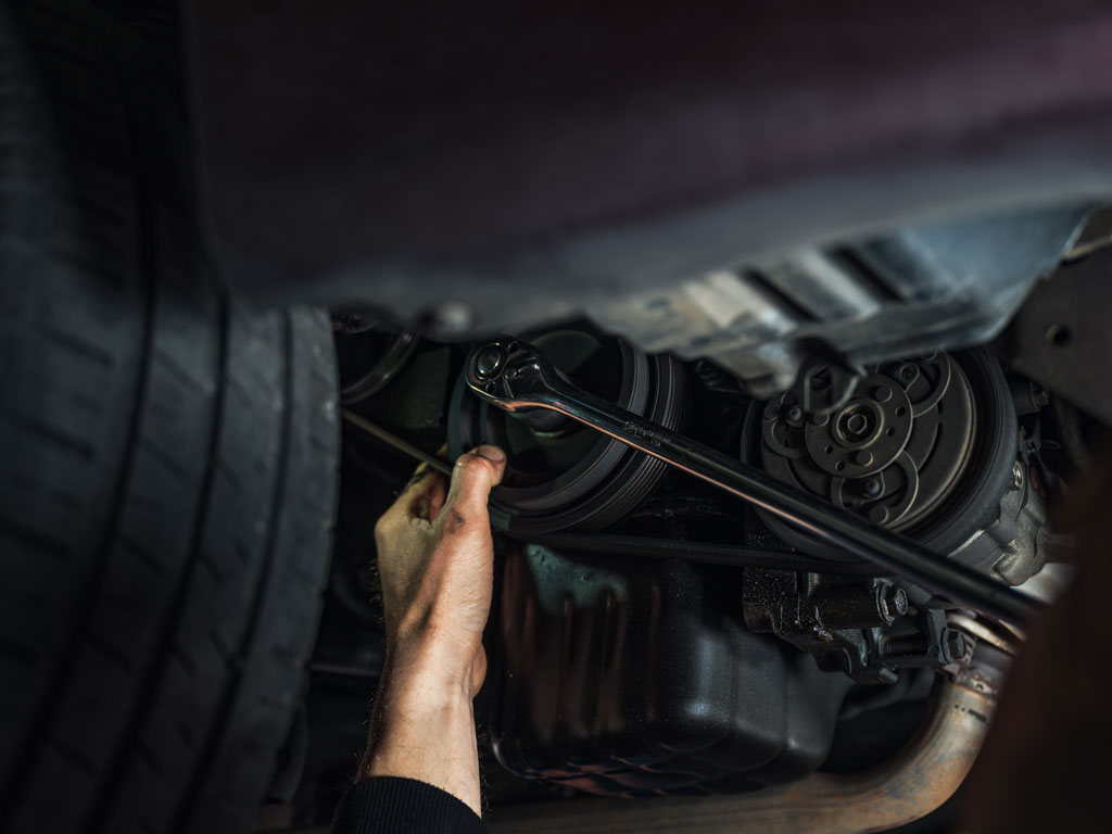 Mechanic performing general car repairs underneath vehicle at Modbury Motors