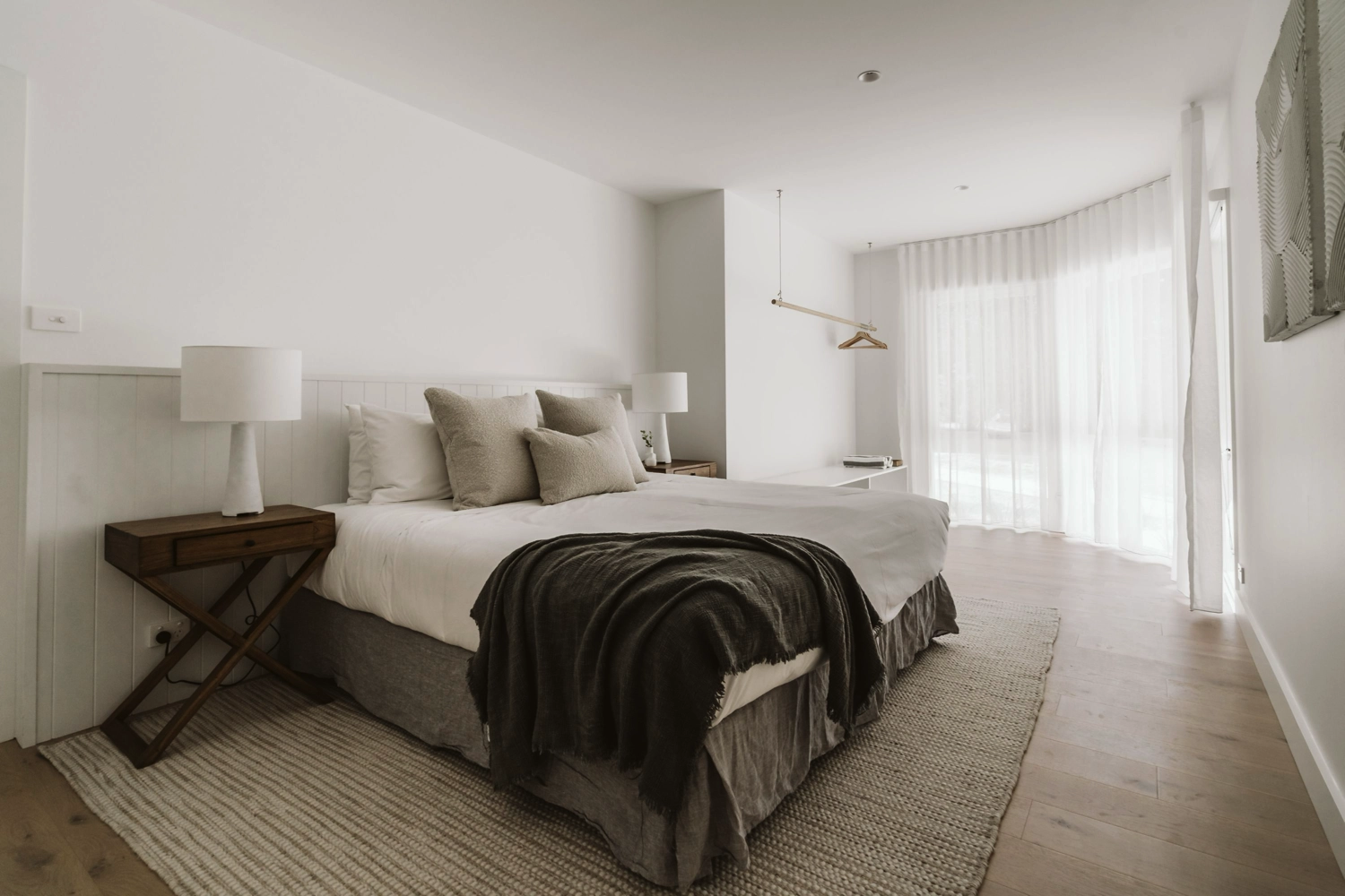 Aerial view of The Hideaway, a tiny studio with a black roof, nestled among dense green trees and a dirt clearing, featuring a wooden deck and scattered outdoor furniture—perfect for a romantic getaway.