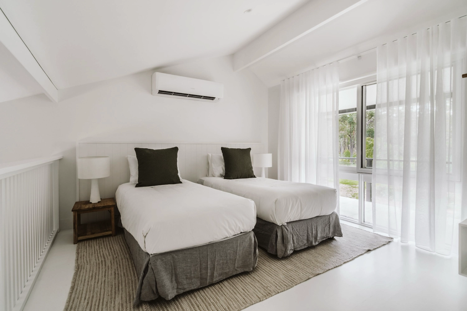 A modern, compact kitchen with light wood cabinets, stainless steel sink, toaster, kettle, and gas stovetop. Perfect for a couples getaway at The Hideaway, this tiny studio features a bed beside the counter for efficient, minimalist living.
