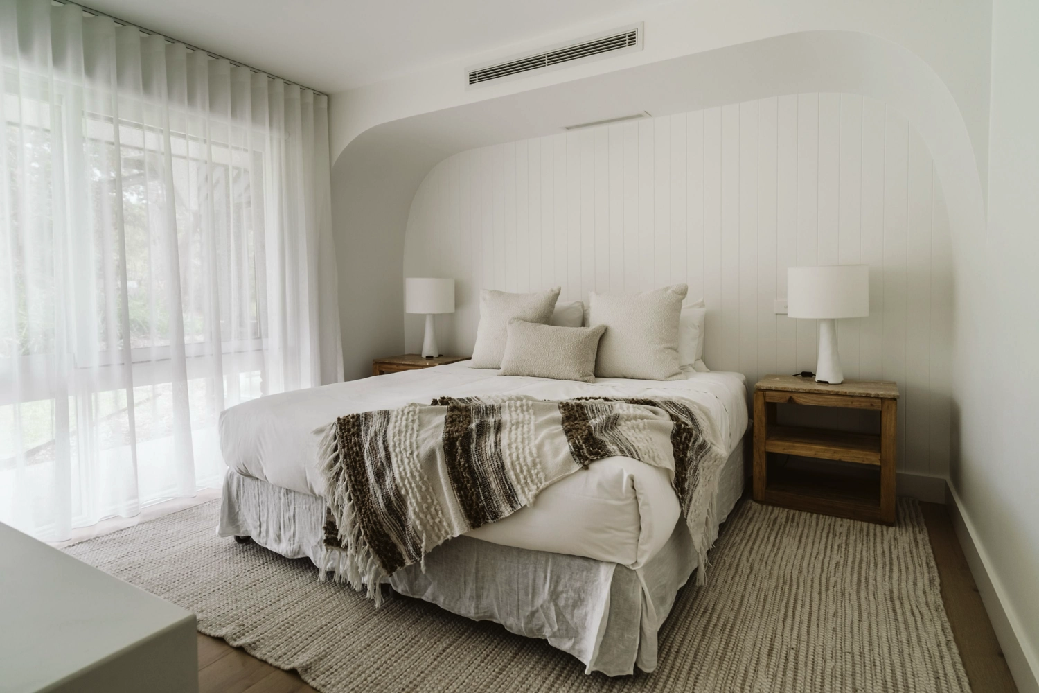 A modern, compact kitchen with light wood cabinets, stainless steel sink, toaster, kettle, and gas stovetop. Perfect for a couples getaway at The Hideaway, this tiny studio features a bed beside the counter for efficient, minimalist living.