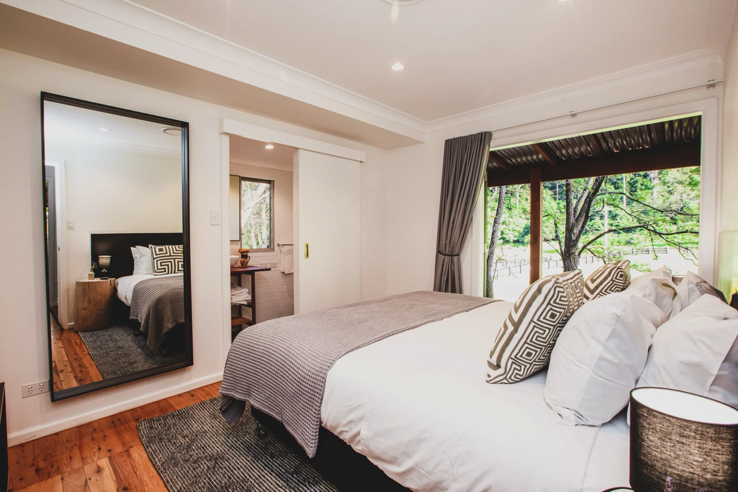 A modern, compact kitchen with light wood cabinets, stainless steel sink, toaster, kettle, and gas stovetop. Perfect for a couples getaway at The Hideaway, this tiny studio features a bed beside the counter for efficient, minimalist living.