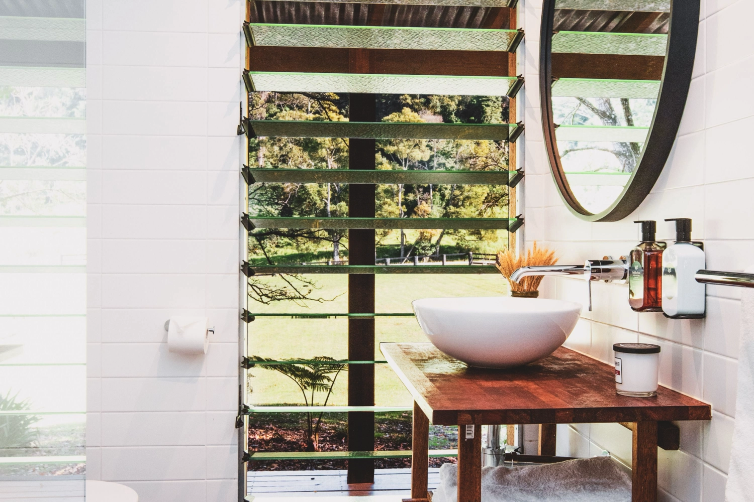 A modern, minimalist bedroom in The Hideaway features light wood-paneled walls, a neatly made bed with white sheets, a small wooden nightstand, and a wall-mounted reading light—perfect for a romantic couples getaway or cozy tiny studio retreat.