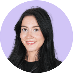 Portrait of a smiling woman with long black hair against a light purple background.