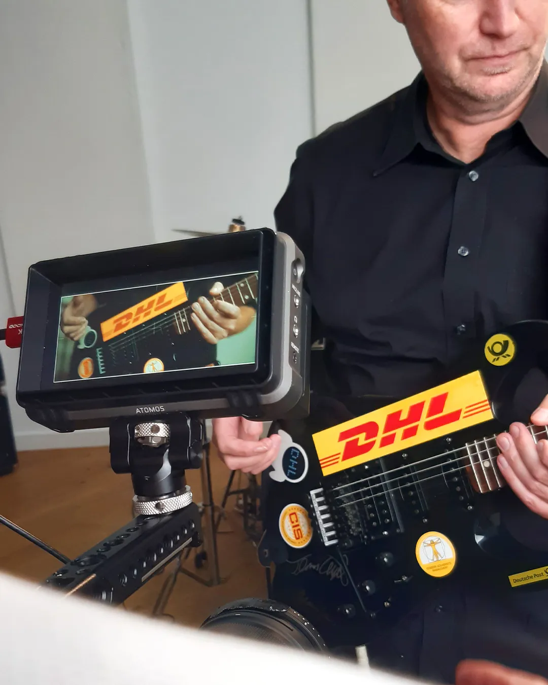 Auf einem Kamerabildschirm ist eine Gitarre mit DHL-Aufkleber zu sehen.
