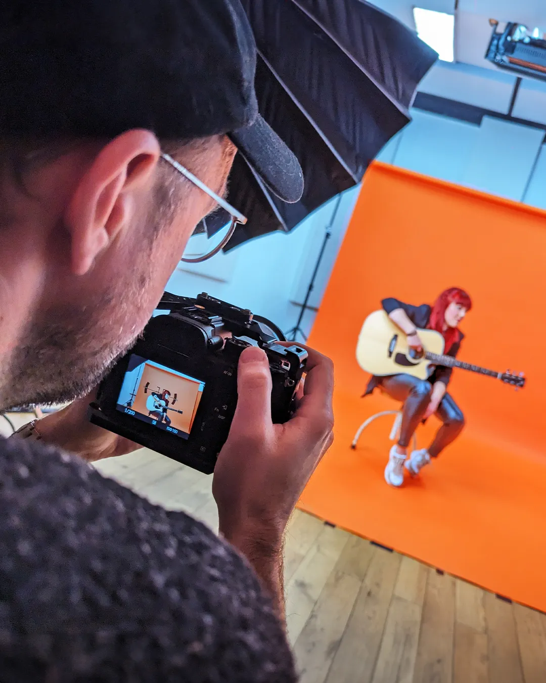Eine Frau spielt Gitarre vor einer orangenen Wand und wird fotografiert
