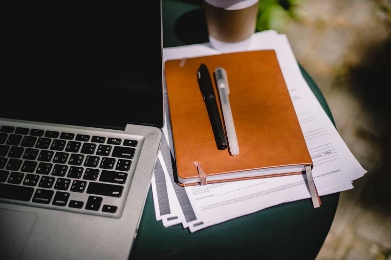 A book, pen, and a laptop is placed on the table