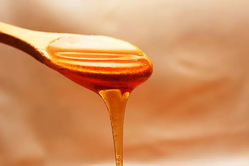 A spoonfull of honey is shown in the image